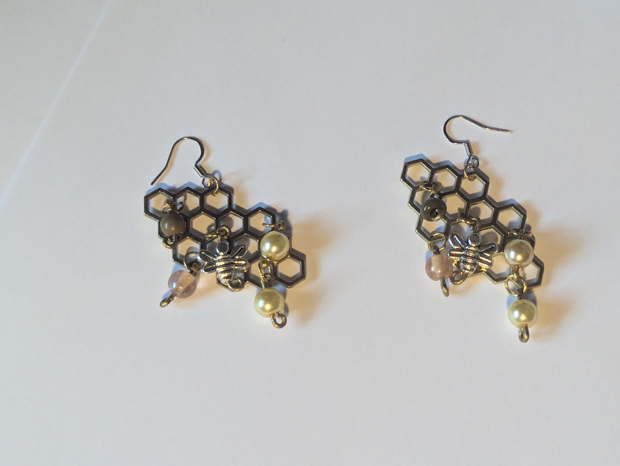 Honeycomb metal design with beads attached to it and a bee charm